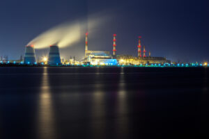 old thermal 450 megawatt power plant at night with artificial lake on foreground